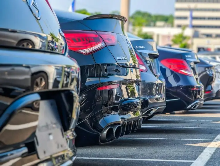 Car-lined parking lot outside a dealership, representing car buyer consulting to help avoid scams, hidden fees, and save money.