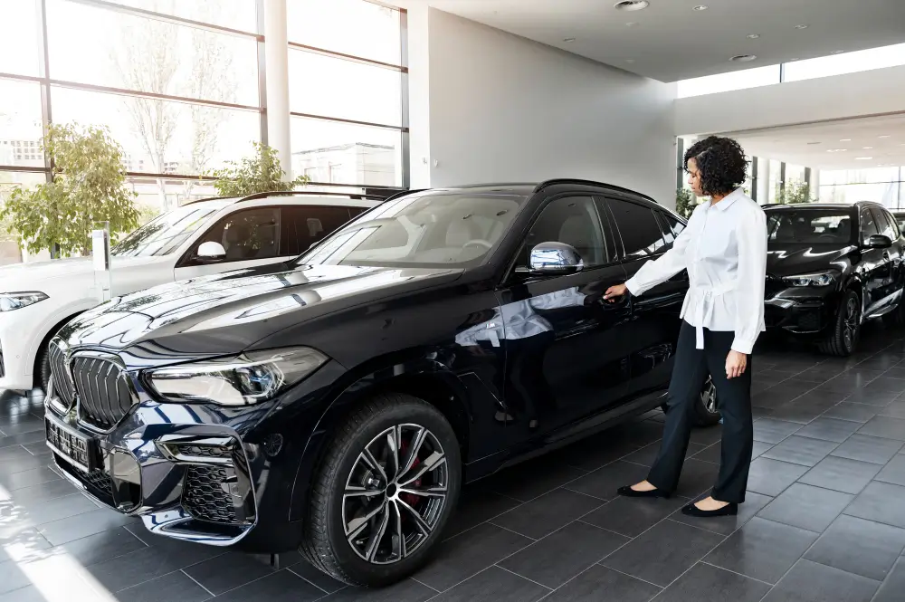 Woman checking a car inside a dealership, illustrating car buyer consulting to avoid scams, hidden fees, and secure a better deal.